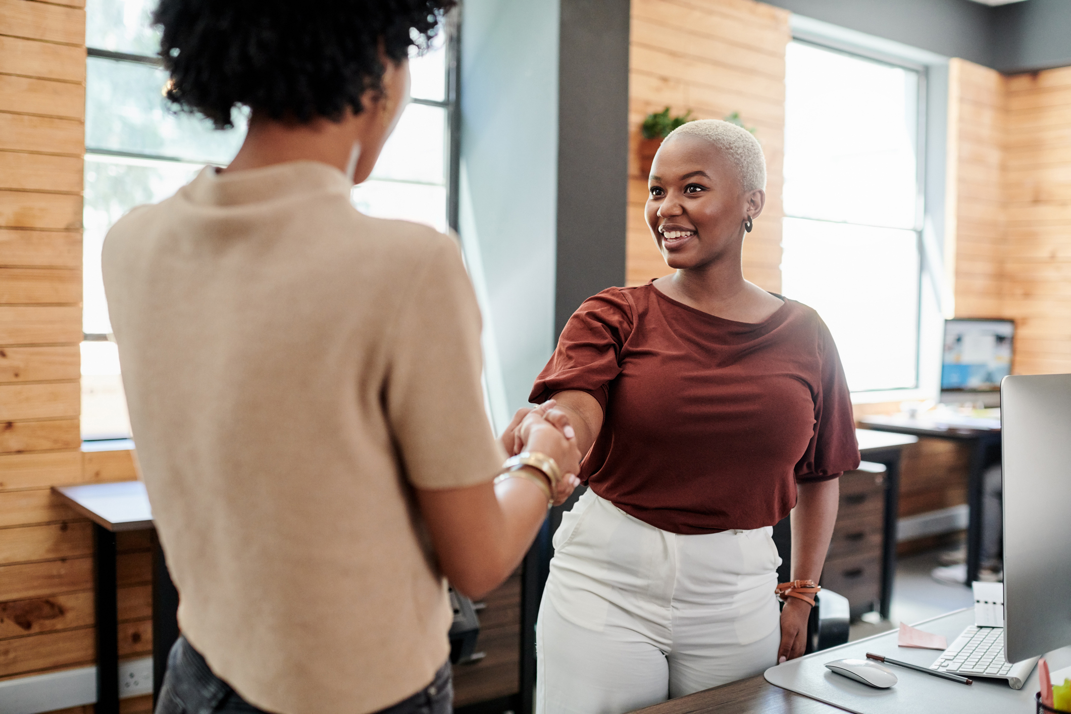 young women shaking hands office